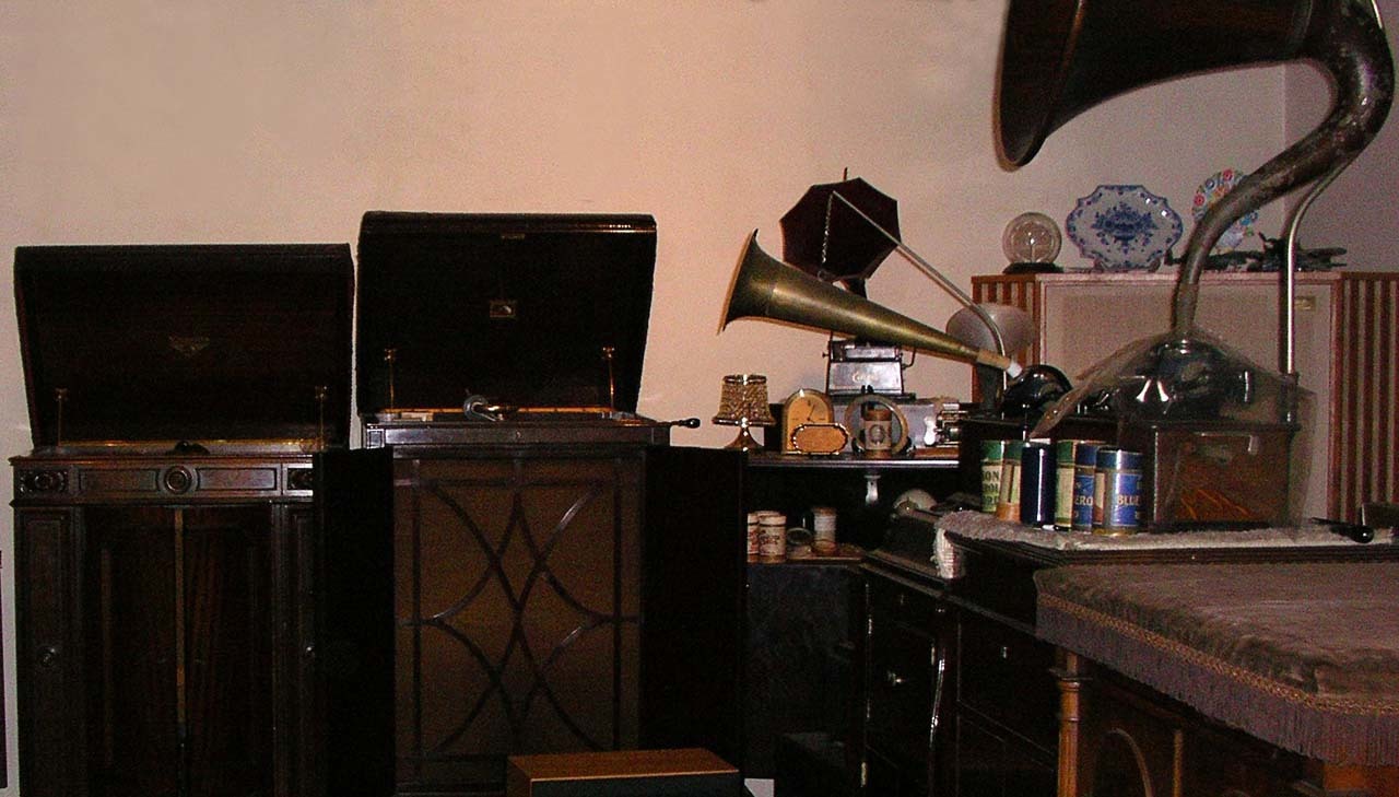 名機とされる数台の蓄音機で、左側にある箱型の２台はディスク型で、右側のラッパ付きのものはシリンダー型